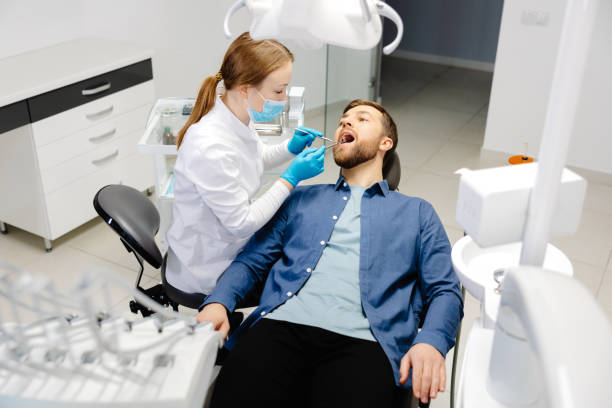 a handsome man is sitting in a chair at a womans appointment at the dentists office 2