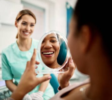 close up of black woman looking at her teeth after dental procedure at dentists office 1