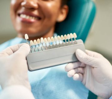 close up of dentist chooses right shade of implants during dental appointment with female