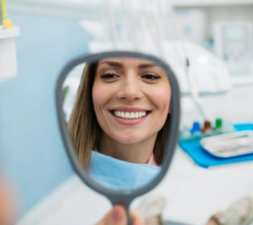 a happy woman looking herself in the hand held mirror 1
