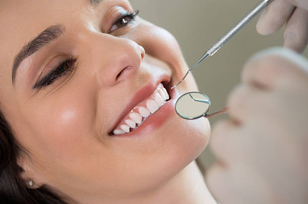 a young woman baring her teeth for the dentist to inspect