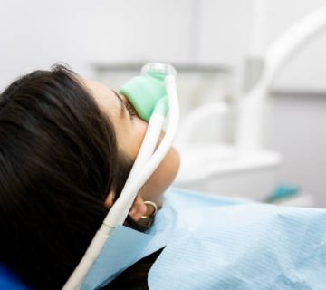 an adult woman sits in a dentists clinic wearing a nasal mask to inhale nitrous oxide dentist 2