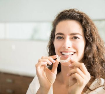 beautiful patient holding orthodontic retainers in dental clinic