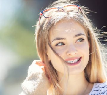 beautiful young blonde girl wearing dental braces smiling and looking to the side 2