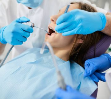 close up of dentist cleaning teenage girls teeth during dental procedure at dentists office