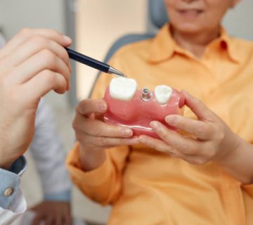 closeup of unrecognizable dentist pointing at tooth model 2