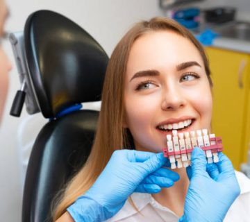 dentist selects a shade of teeth whitening using shade guide to young patient with perfect