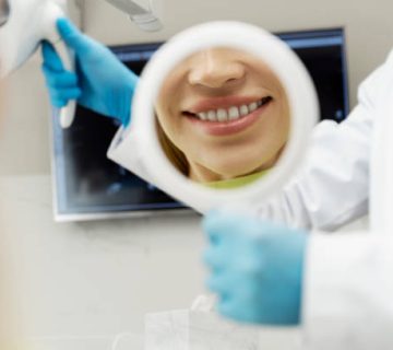 dentist showing perfect smile to patient with mirror in dental clinic