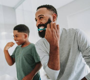 father teaching son to brush teeth