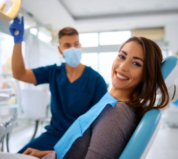 happy woman having dental treatment at dentists office and looking at camera 1
