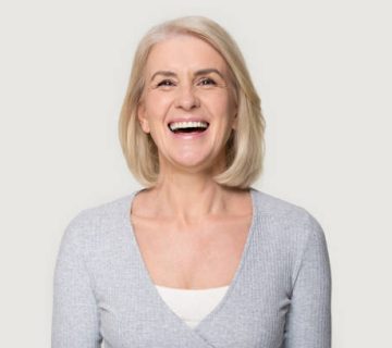 headshot happy aged female laughing posing on grey studio background