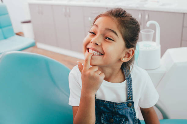 mixed race little patient showing her perfect toothy smile while sitting dentists chair 1