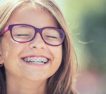 portrait of a happy smiling teenage girl with dental braces and glasses