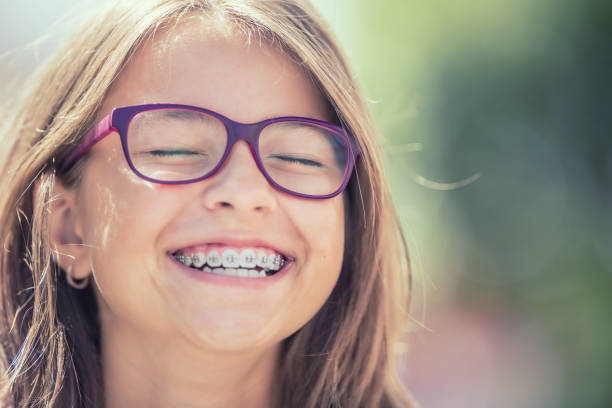 portrait of a happy smiling teenage girl with dental braces and glasses