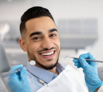 portrait of happy arab man sitting at dentist chair in modern clinic 1