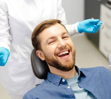 portrait of happy man sitting at dentist chair in modern clinic and smiling patient enjoying