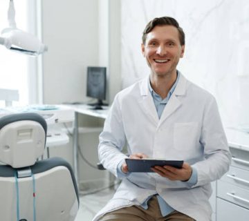 smiling male dentist looking at camera in dental clinic