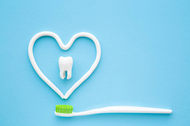 toothbrush with green bristles on pastel blue background heart shape created from paste white