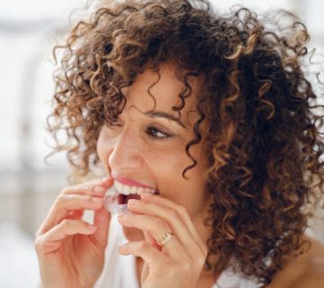woman in bed in the morning using clear teeth aligners