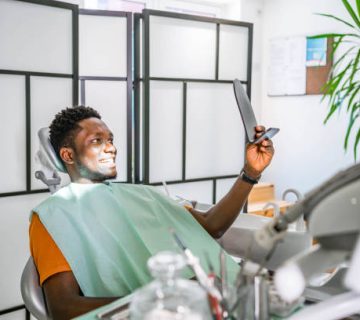 young man checking teeth in mirror at the dentists office