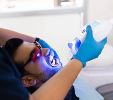 young man with glasses getting whitening laser treatment