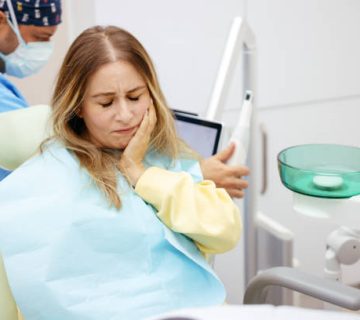 young woman feeling pain holding her cheek with hand at dentists office toothache concept 2